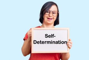 young woman with Down Syndrome holding a sign for self-determination